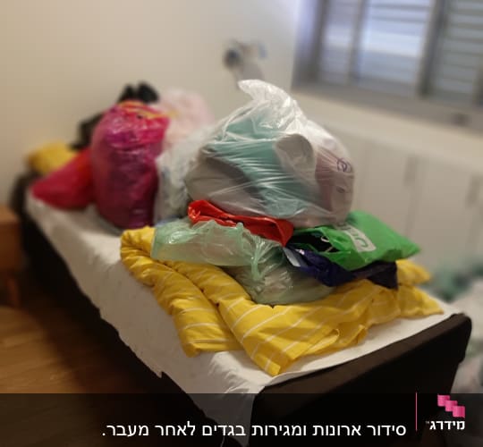 מיטה עם שקיות בגדים ופריטים לארגון